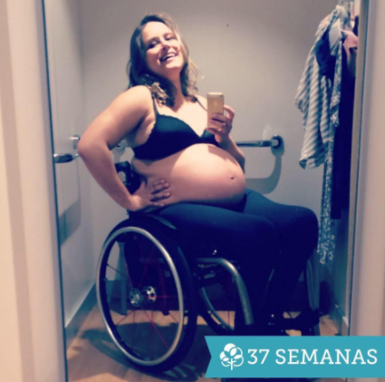 mulher branca, loira, grávida, em uma cadeira de rodas, se fotografa no espelho